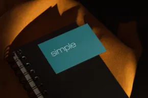 A notebook with a turquoise cover labeled "template" rests on a black surface partially covered by a yellow cloth, illuminated by dim, moody lighting. - PSD Mockup