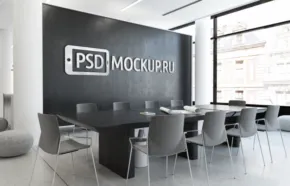 Modern office conference room with a large black wall labeled "mockup", a long table, gray chairs, and large windows letting in natural light. - PSD Mockup