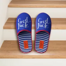 A mockup of a pair of blue flip-flops with "good luck" printed on them is placed neatly on a wooden step. - PSD Mockup