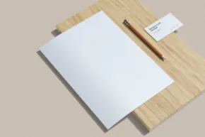 A white sheet of paper, serving as a template, on top of a wooden table. - PSD Mockup