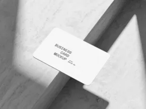 A monochrome mockup of a business card with minimal design details, placed on a textured stone surface. - PSD Mockup