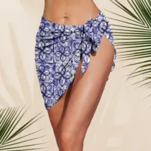 A woman wearing a blue floral sarong on a sandy template with palm leaf shadows. - PSD Mockup