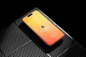 Yellow and orange gradient smartphone mockup with a central camera on a textured black surface. - PSD Mockup