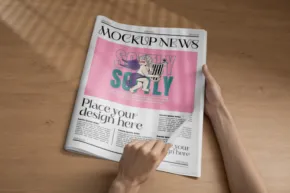 Person reading a newspaper with exaggerated, fictional headlines using a mockup template. - PSD Mockup