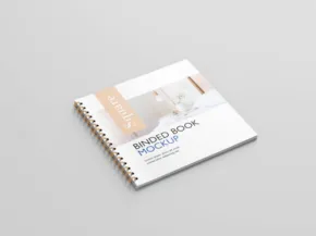 A spiral-bound notebook with a printed cover labeled "recipe book - meal ideas" resting on a gray surface, serving as a mockup template. - PSD Mockup