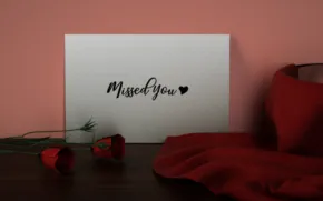 A canvas with the words "much love" and a heart symbol, accompanied by red roses and a draped red fabric on a pink background serves as an ideal mockup. - PSD Mockup