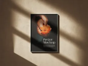 A mockup of a framed poster on a wall depicting a hand holding a fiery object, illuminated by diagonal sunlight casting shadows. - PSD Mockup