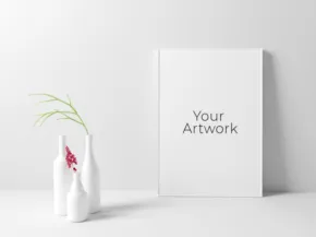 A minimalistic mockup display with a blank canvas on a wall and a vase with a plant on the side ready for an artwork presentation. - PSD Mockup