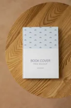 A book with a simple patterned cover resting on a wooden surface, serving as an ideal mockup. - PSD Mockup