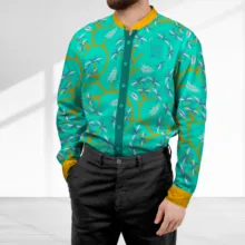 Man in a vibrant teal floral jacket and black trousers standing in a brightly lit room with a white mockup background. - PSD Mockup