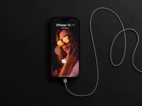 A mockup of an iPhone on a black surface connected to white earphones, displaying a colorful template wallpaper of a woman wearing sunglasses. - PSD Mockup
