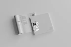Two mockup magazines with one rolled and the other closed, placed on a plain surface. - PSD Mockup