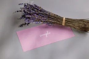 A bunch of lavender tied with twine, resting on a pink envelope with the word "template" written on it. - PSD Mockup