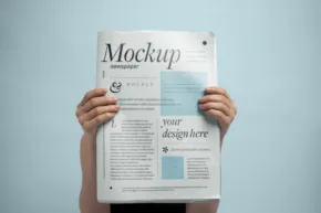 Person holding a newspaper with the word "template" on the front page against a blue background. - PSD Mockup