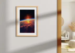 A framed picture of a sunrise over mountains, serving as a template, hanging on a wall in a room with modern decor. - PSD Mockup