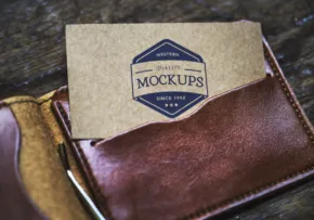 A leather wallet and a craft envelope labeled "mockup" resting on a wooden surface, symbolizing professional branding materials. - PSD Mockup