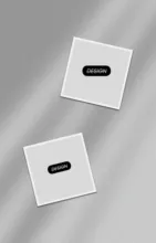 Two white square mockup buttons with a black line or slot in the center, resembling minimalistic design elements or abstract icons, positioned diagonally on a plain gray background. - PSD Mockup
