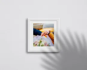 Framed photograph hanging on a white wall casting a soft shadow, serving as an ideal template. - PSD Mockup