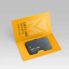 A template of a black gift card inside a vibrant orange sleeve adorned with a white chevron design and text. - PSD Mockup