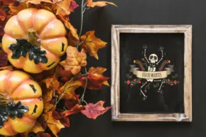 A Halloween-themed template with pumpkins, autumn leaves, and a skeleton decoration within a picture frame. - PSD Mockup