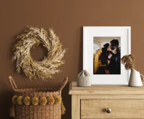 A cozy interior scene featuring a framed mockup on a wall shelf beside a wheat wreath and decorative objects, with a textured basket placed on the floor. - PSD Mockup