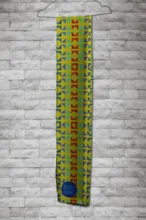 A colorful scarf with traditional African patterns in a mockup hanging on a white brick wall. - PSD Mockup
