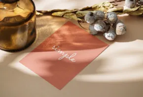 A stylish flat lay of a copper-colored card with the word "template" written across it, accompanied by a gold-rimmed bowl and decorative twigs with cotton bolls, bathed in soft - PSD Mockup