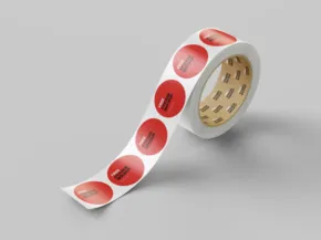 A mockup of a roll of tape with a design featuring red circles on a white background, partially unrolled, against a light grey surface. - PSD Mockup