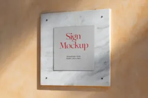 A square marble wall sign with a smaller gray square in the center displaying the text "Sign Template" in red, all mounted on a beige wall. - PSD Mockup