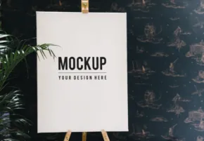 Blank template mockup on an easel with a decorative plant beside it against a dark patterned background. - PSD Mockup