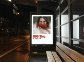 A bus stop on a rainy night featuring a mockup of an advertisement with a woman wearing a red mask. - PSD Mockup