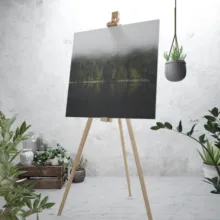 A dark, abstract painting on an easel in a minimalist room with green plants serves as a perfect template. - PSD Mockup
