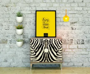 A zebra-striped cabinet against a brick wall with a template of yellow-framed artwork above reading "stay wild child," flanked by wall-mounted plant holders and a hanging light. - PSD Mockup