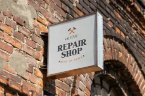 A template featuring a sign labeled "repair shop" mounted on a brick wall with a small logo of a wrench and hammer crossed. - PSD Mockup