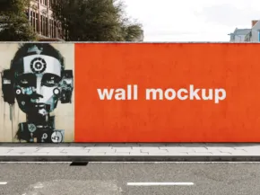 A street wall template featuring a large orange panel with the words "mockup" and a black-and-white artistic stencil of a face on the left. - PSD Mockup