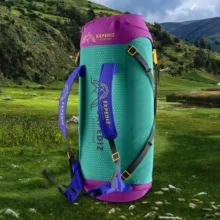A teal and purple backpack mockup standing in a grassy field with a mountainous backdrop. - PSD Mockup