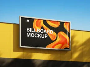 Billboard template with a vibrant orange and yellow design mounted on a bright yellow wall under blue sky. - PSD Mockup