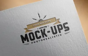 Close-up of a business card featuring a gray "mockup template" logo with decorative elements on a textured cream background. - PSD Mockup