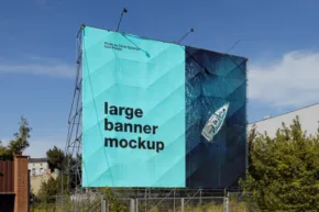Large turquoise billboard showcasing a mockup template with the text "large banner mockup" beside a highway, under a clear blue sky. - PSD Mockup