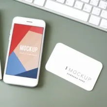 A smartphone and business card on a desk displaying mockup template designs. - PSD Mockup