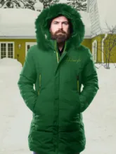 Man in a green winter coat with hood standing in front of a snow-covered background, which serves as a perfect mockup. - PSD Mockup
