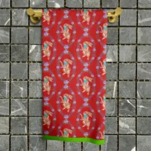 A red towel with a floral pattern hanging on a gold rack against a grey tiled wall, perfect as a mockup template. - PSD Mockup