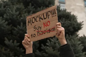 Person holding a template for a protest sign that reads "wake up!!! say no to racism. - PSD Mockup