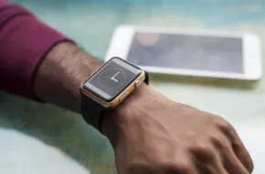 A person wearing a smartwatch with a mockup tablet in the background. - PSD Mockup