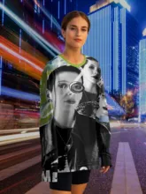 A woman wearing a black and white graphic sweatshirt mockup stands on a city street with colorful light streaks in the background. - PSD Mockup