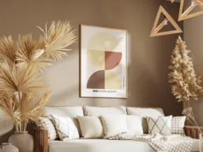 A stylish living room featuring a beige sofa with plush pillows, a framed abstract art piece on the wall, and decorative dried pampas grass in the corner. - PSD Mockup