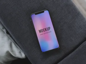 Smartphone with a colorful screen displaying the template "mockup" resting on a gray fabric surface. - PSD Mockup