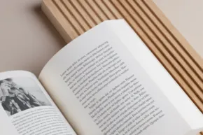 An open book featuring text and a black-and-white image on one page, serving as a template, stacked on top of other closed books. - PSD Mockup