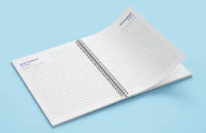 Open notebook with blank grid pages serving as a template on a light blue background. - PSD Mockup