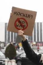 Person holding an anti-war protest sign mockup outdoors. - PSD Mockup